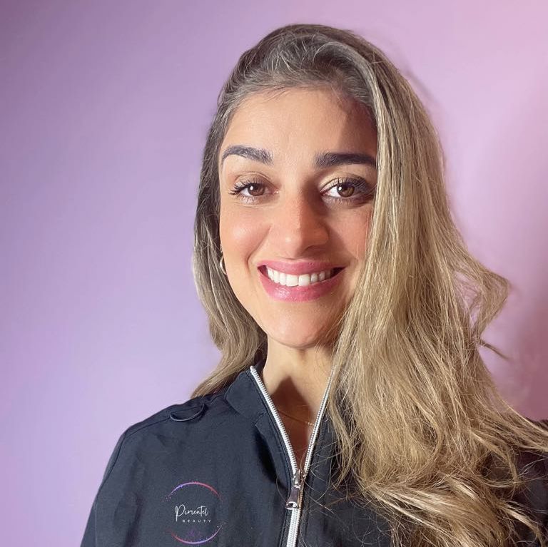 Dame med blå jakke foran rosa vegg